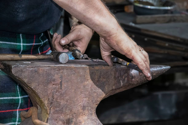 istock Blacksmith in kilts dirty hands - close-up - working metal on an anvil - selective focus 1286205213