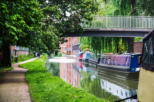 Canal with boats tied up under bridge and reflections in water near Oxford England