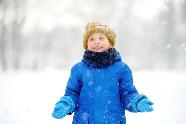 istock Little boy having fun playing with fresh snow during snowfall. Admiring baby catching snowflakes on gloves. Active outdoors leisure for child on snowy winter day. 1286210049