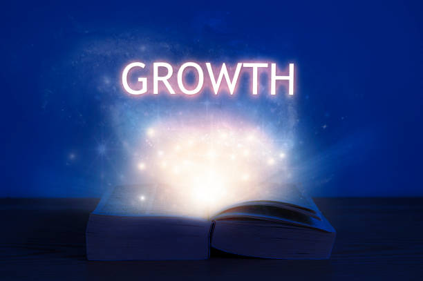 istock Open book with growth inscription. Light coming from open book with word growth. 1286211461