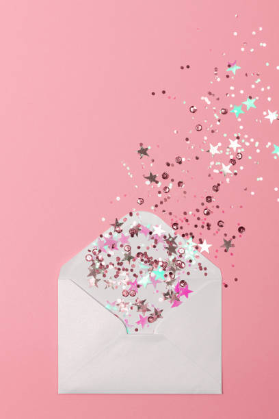 istock Sparkling confetti scattered from envelope on pastel pink background. 1286211738