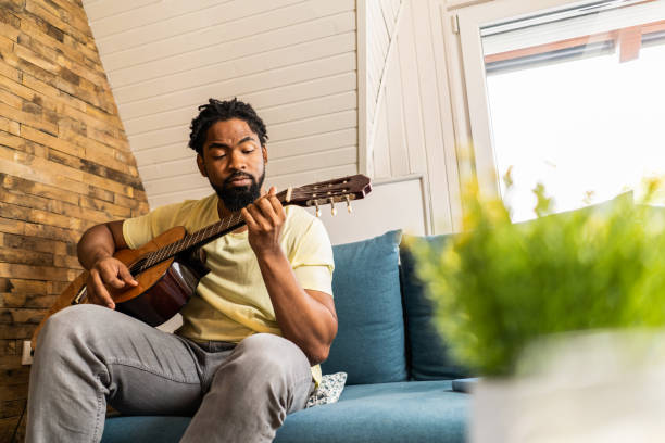 istock Man playing a guitar at home. 1286216019