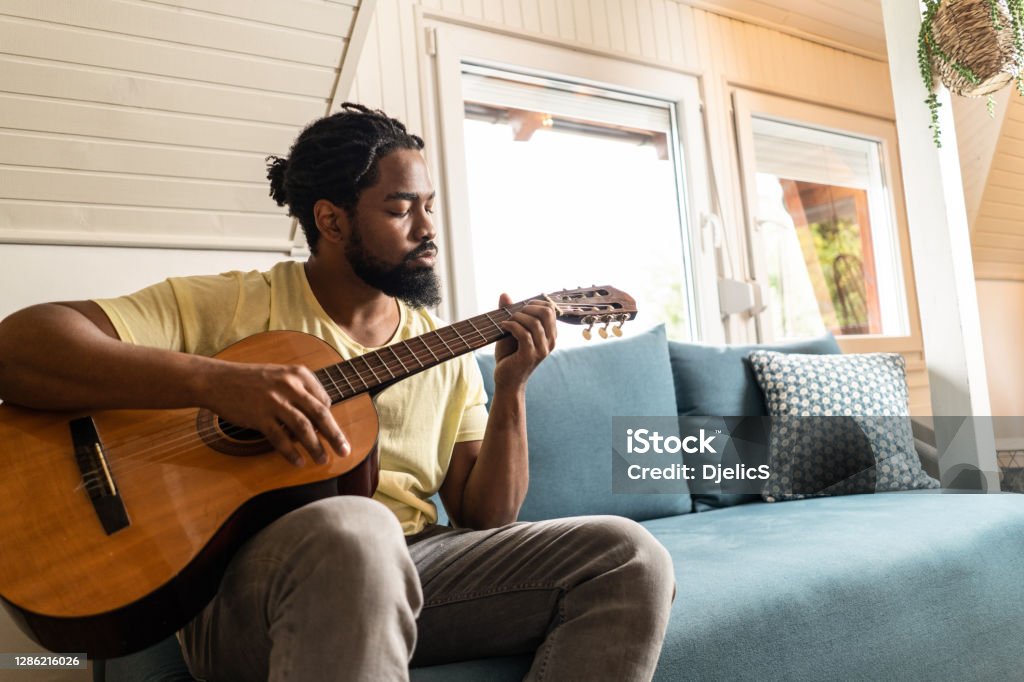 Man playing a guitar at home. African American man playing a guitar at home. Guitar Stock Photo