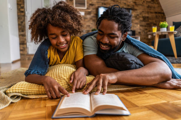 père et fille heureux lisant un livre ensemble. - family reading african descent book photos et images de collection