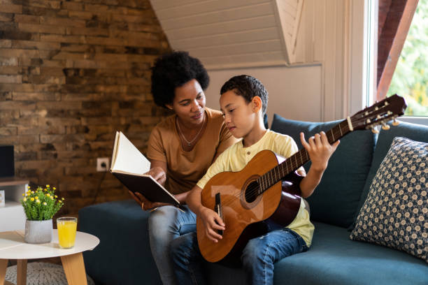 istock Mother teaching her son to play guitar. 1286216312
