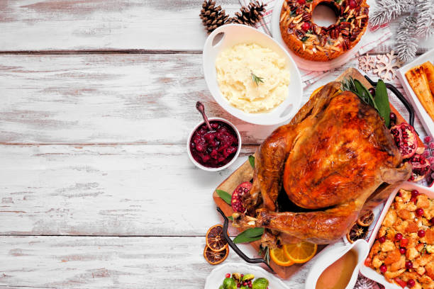 Traditional Christmas turkey dinner. Overhead view side border on a rustic white wood background.