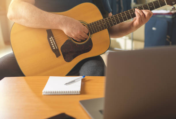 istock Man learns to play the guitar using online video lessons. 1286220065