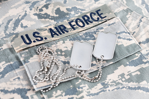 US AIR FORCE branch tape and dog tags on digital tiger-stripe pattern Airman Battle Uniform (ABU) background