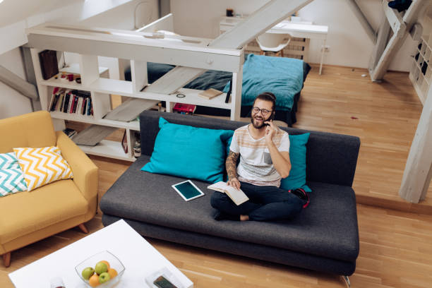 istock Young man studying at home and talking on the phone 1286224300