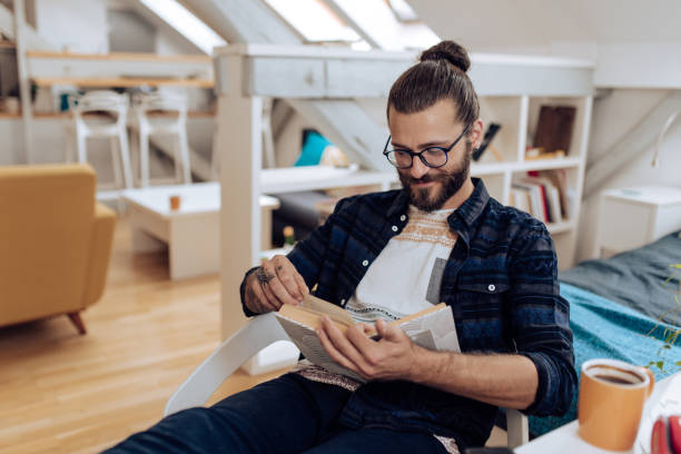 istock Young man reading a book and relaxing at home 1286224360