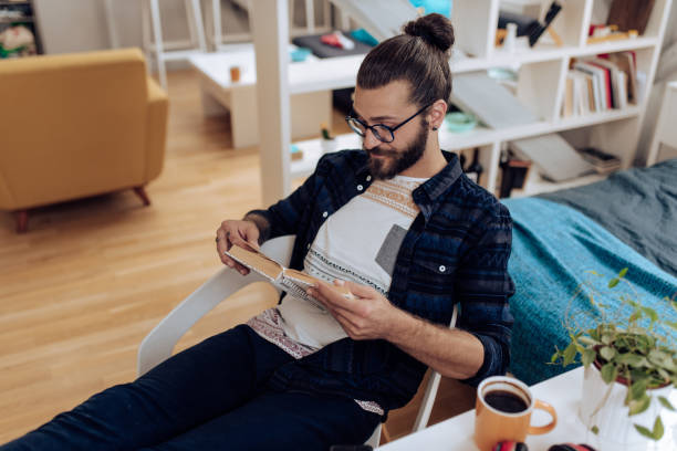 istock Young man relaxing and reading at home 1286224364