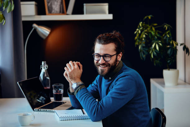 uśmiechnięty freelancer siedzący w swoim biurze i pracujący nad ważnym projektem. - computer programmer laptop men nerd zdjęcia i obrazy z banku zdjęć