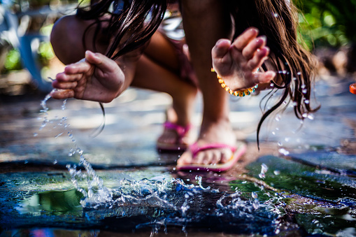 Child Playing with water on the ground during a Summer afternoon