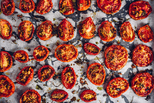 Prepared Sun Dried Tomatoes with Olive Oil and Herbs on Parchment Paper. View from Above.