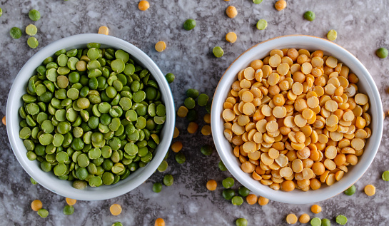 Uncooked yellow and green split peas in bowls.  Overhead view with horizontal composition.