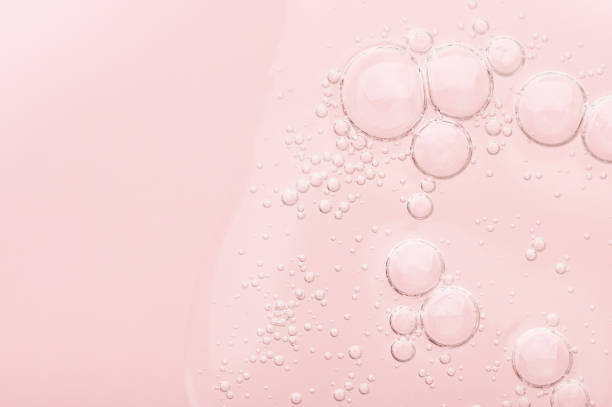 la texture d’un gel transparent liquide pour le nettoyage du visage. échantillon de sérum d’huile avec des bulles sur un fond rose. produit de beauté cosmétique hydratant pour les soins de la peau. lotion pour soins de la peau sèche - prélèvement de sérum photos et images de collection