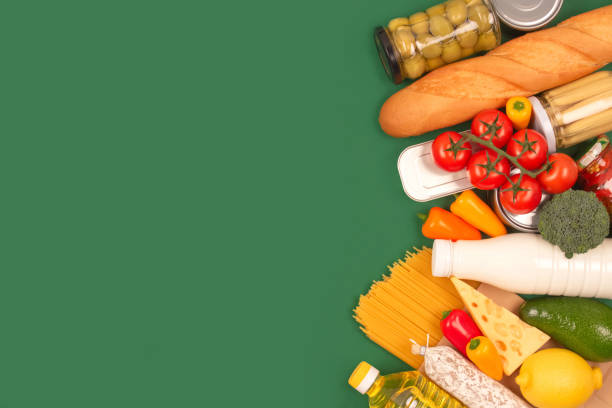 istock Different groceries, food donations on green background with copyspace - pasta, fresh vegatables, canned food, baguette, cooking oil, tomatoes, cheese. Food donations, food bank, food delivery concept 1286240799