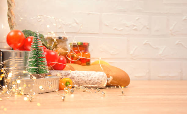 Christmas donations - food donations on light background with copyspace - pasta, fresh vegatables, canned food, baguette, cooking oil with Christmas decorations. Food bank. Selective focus