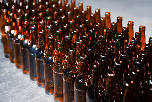 Rows of glass beer bottles brown color close up