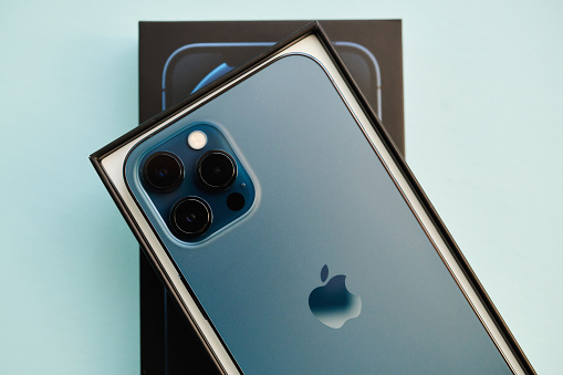 17 November 2020 - Peyton, Colorado, USA: A studio shot of a brand new iPhone 12 Pro Max in Pacific Blue in the box it was shipped in. Shot on a pale blue surface