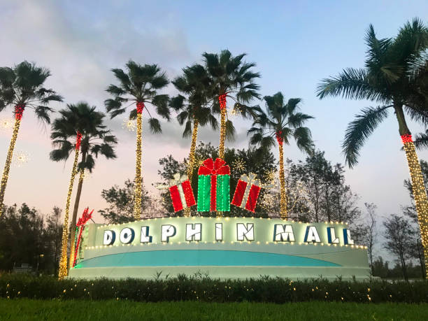 Dolphin Mall Shopping Entrance at sunset, Miami, Florida, USA Miami, Florida, United States - November 17, 2020: General landscape view of Dolphin Mall Shopping Center sign entrance from Northwest 12th Street in Miami, during the second wave of Covid-19 Corona Virus Quarantine in a sunny winter sunset afternoon. The Shopping Mall is located at 11401 NW 12th St, in Sweetwater, Miami-Dade County. The entrance is decorated with Christmas Lights and ornaments welcoming the most higher season of the year for sales.

The shopping is the biggest outlet in Miami Area, has 240 retails, the most famous brands around the world as: Adidas, Nike, Calvin Klein, Victory Secrets and much more, divided into three districts: Playa (Beach), Ramblas (Boulevards), and Moda (Fashion), and has nine zones. kendall stock pictures, royalty-free photos & images