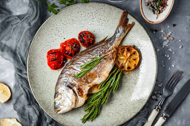 istock Baked dorado fish on a plate with vegetables top view 1286251180