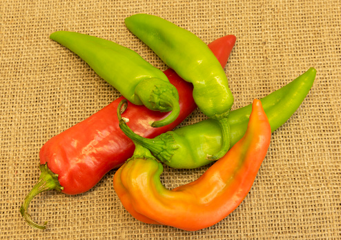 red and green anaheim peppers arranged on burlap.
