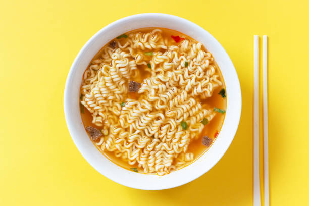 Instant noodle soup in a white bowl on yellow background top view. Instant noodle soup in a white bowl on a yellow background top view. fast food restaurant photos stock pictures, royalty-free photos & images