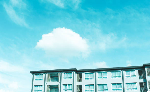 A building under white fluffy clouds and blue pastel sky in a sunny day