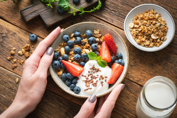 istock Granola bowl with berries and yogurt in female hands 1286268244