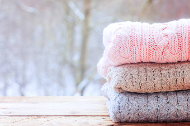 istock Cozy stack of knitted sweaters on wooden table on winter nature background. 1286269043