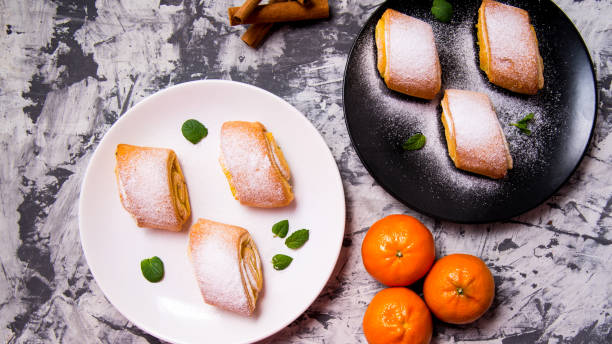 istock Strudel baking,powdered cake with Mandarin mint leaves,cinnamon sticks on a white,black plate on a black and white background with a space for text,top view 1286271075