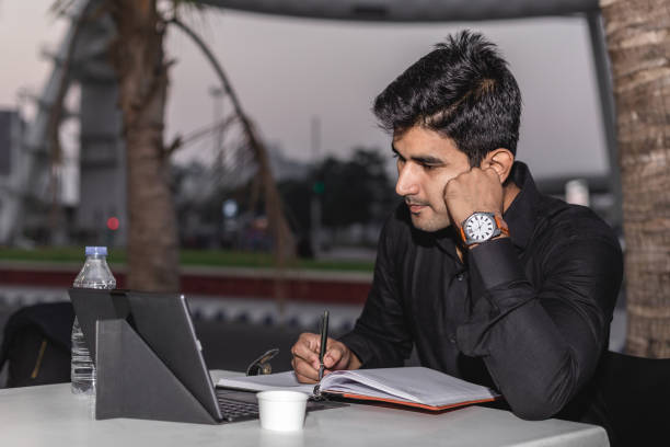 jeune homme utilisant l’ordinateur portatif ou la tablette numérique et l’écriture. - restaurant business person setting the table clothing photos et images de collection