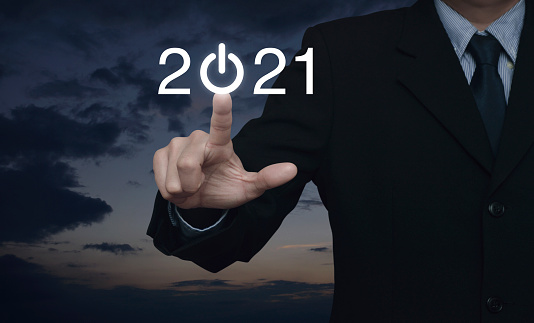 Businessman pressing 2021 start up business flat icon over sunset sky, Business happy new year cover concept