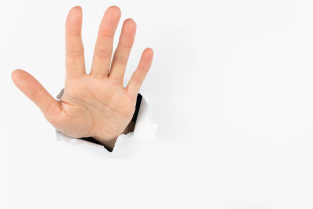 istock A hand shows a welcome gesture from a hole in a white wall. Conceptual greetings from the past or years later. 1286272247