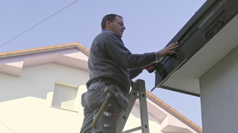 Worker on roof installing metal tile