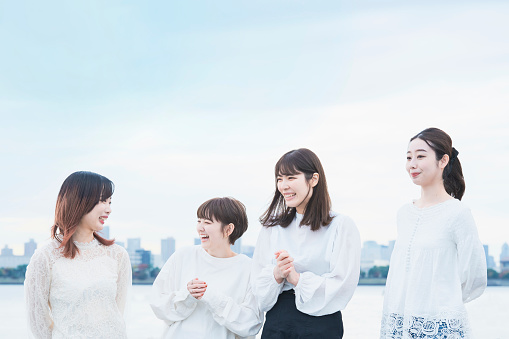 4 Japanese women wearing white tops and talking with a smile