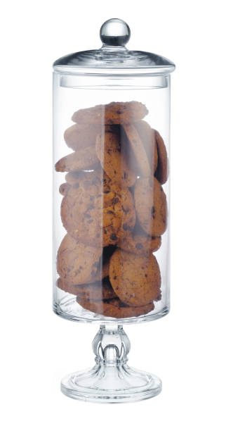 istock Glass cookie jar with chocolate chip cookies inside on white background 1286275811