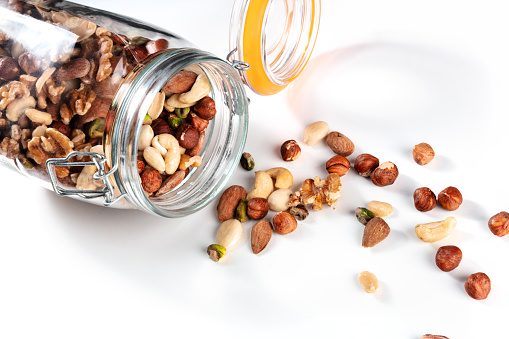 Many different nuts in a mason jar, on a white background