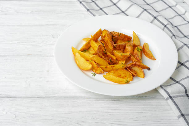 istock Fried potato wedges in plate on white wooden table 1286277701