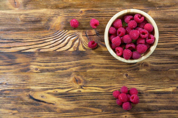 istock Full bowl of raspberries on wooden table with copy space 1286280123