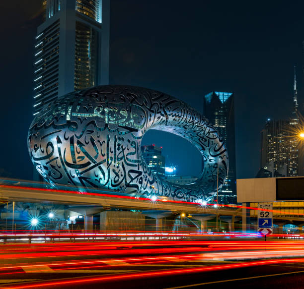 le musée du futur dubaï la nuit avec des sentiers lumineux. le bâtiment emblématique de dubaï. pour être prêt pour l’exposition universelle 2020 avec la poésie arabe à l’extérieur. - futuristic dubai city traffic photos et images de collection