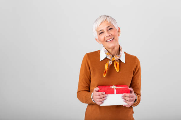 портрет веселой позитивной радостной очаровательной пожилой женщины с прической с рождественской подарочной коробкой в красном пакете с � - white gift caucasian women стоковые фото и изображения