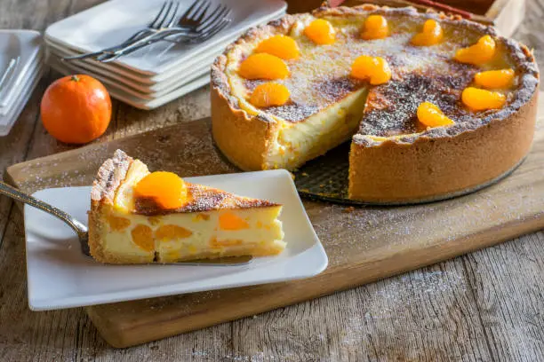 delicious, creamy sour cream custard cake with clementines. Fresh and homemade baked and served on wooden table background from above view