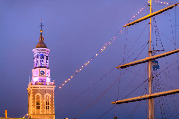 New Tower and old sailing ship in Kampen at night during a cold winter evening in Overijssel, The Netherlands.