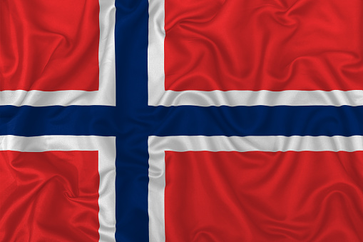 Norway country flag on wavy silk textile fabric background.
