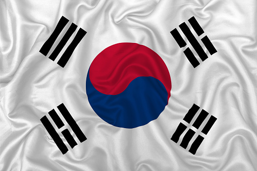South Korea country flag on wavy silk textile fabric background.