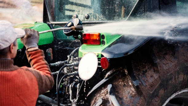 High pressure water cleaning Mature man cleaning dirty tractor  with high pressure water cleaner agricultural equipment stock pictures, royalty-free photos & images