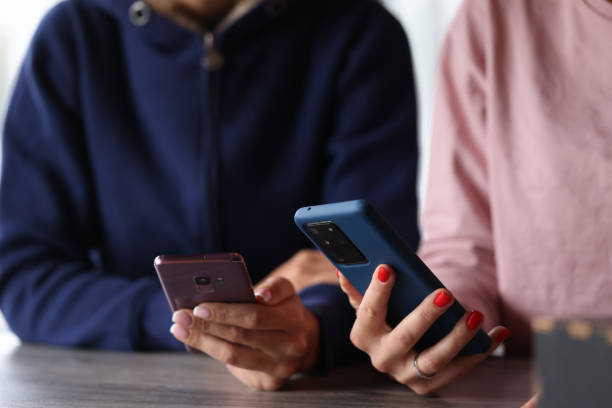 dos mujeres tienen teléfonos inteligentes en sus manos. - ciborg fotografías e imágenes de stock