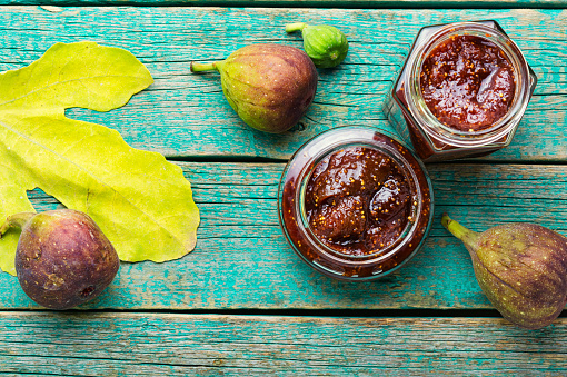 Glass jar with fig jam on rustic wooden table